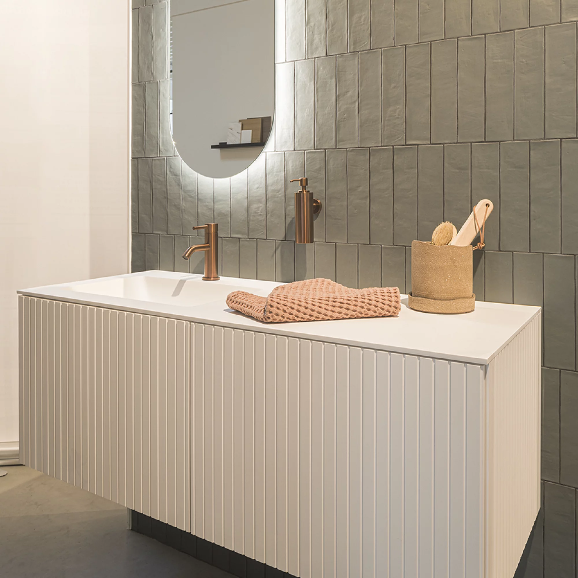 Minimalistisch meubel in mat solid surface met warme koperaccenten